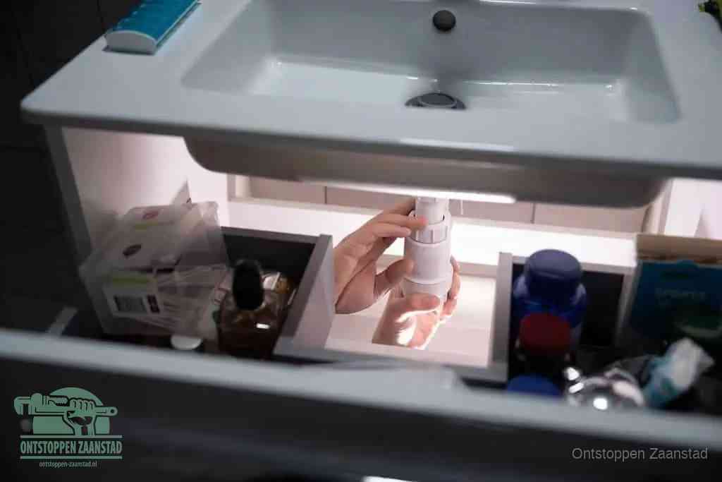 Een pompfles met zeep boven een wastafel, de heet water en afwasmiddel-methode om een vetprop in de afvoer los te maken in Zaanstad