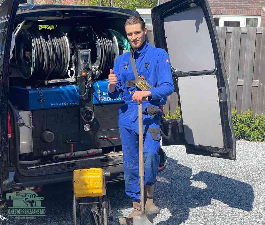 Een tevreden monteur met opgestoken duim naast de bestelbus, slim ingrijpen bespaart kosten bij een verstopte afvoer in Zaanstad