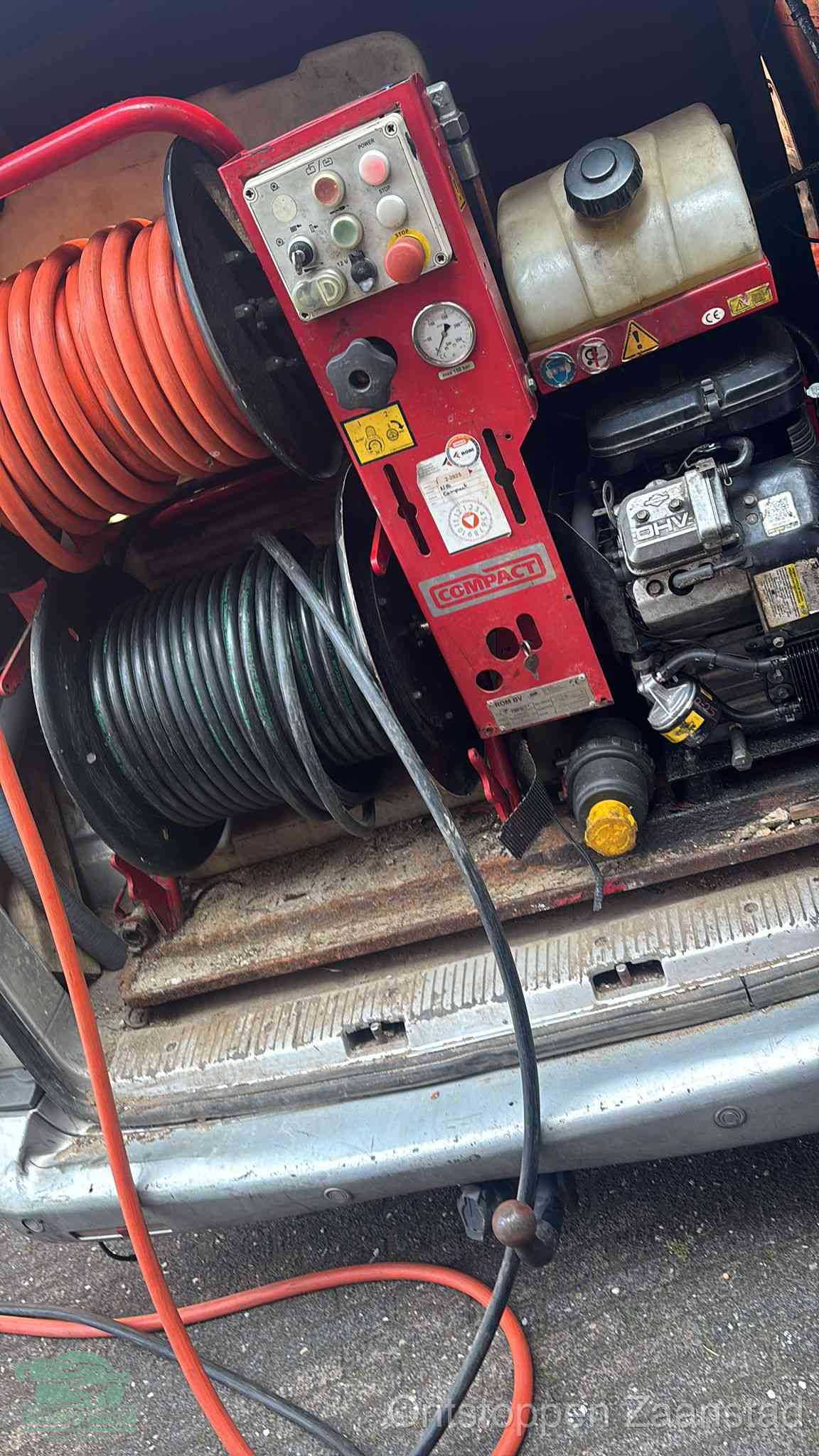 Een rood hogedruk-rioolreinigingstoestel in de laadbak van de bedrijfsbus, apparatuur voor een hardnekkige afvoerverstopping in Zaanstad