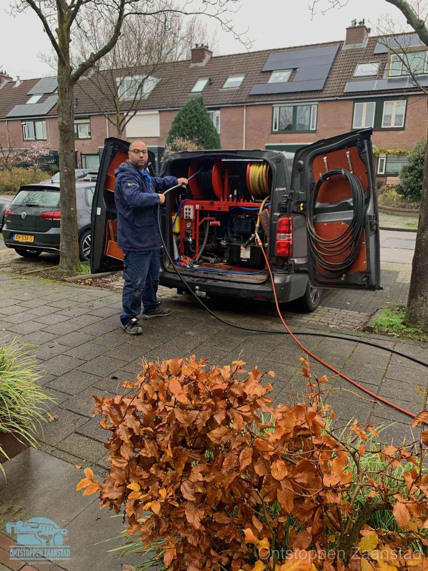 Monteur met rioolreinigingsbus levert rioolservice in de wijk in Zaanstad