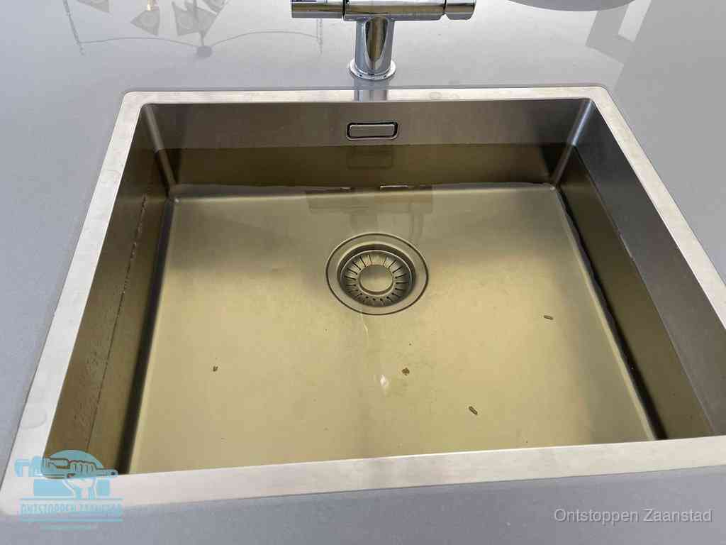 Stilstaand water in een rvs spoelbak dat niet wegloopt, een duidelijk signaal van een gootsteenverstopping in Zaanstad