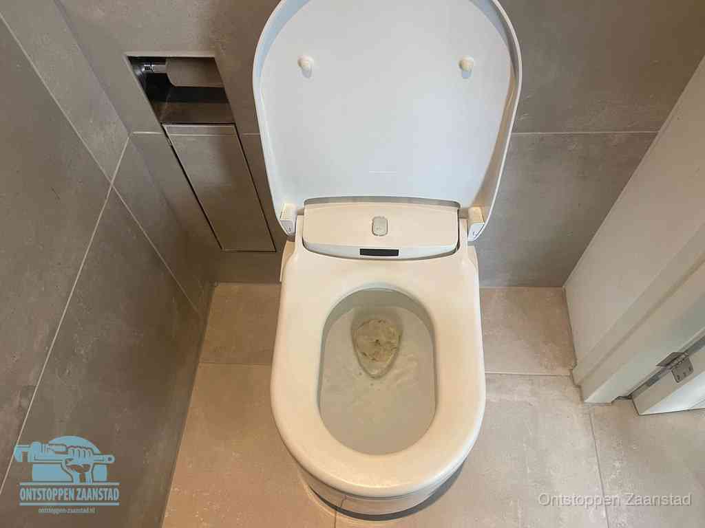 Een wit hangtoilet waarin een prop wc-papier op het water blijft drijven, een duidelijk signaal van een verstopte wc in Zaanstad