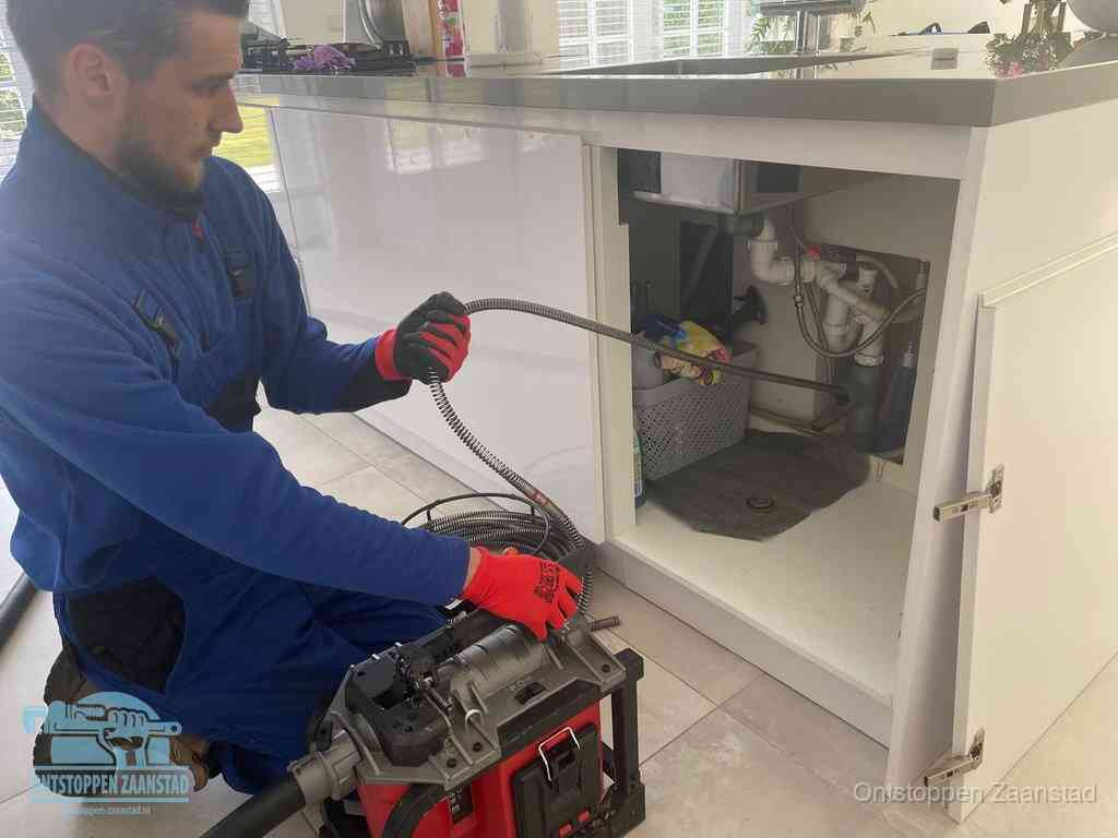 Een monteur reinigt de keukenafvoer grondig met een veermachine om terugkerende gootsteenverstoppingen te voorkomen in Zaanstad