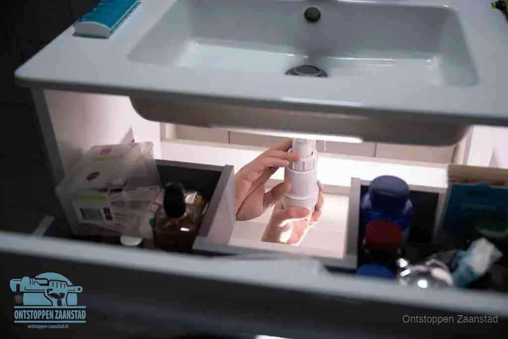 Een pompfles met zeep boven een wastafel in de toiletruimte, de warm water en afwasmiddel-methode om de wc te ontstoppen in Zaanstad
